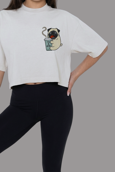 Person wearing a cream off white crop tee with a pug and coffee graphic with text Rise and Grind, and black leggings
