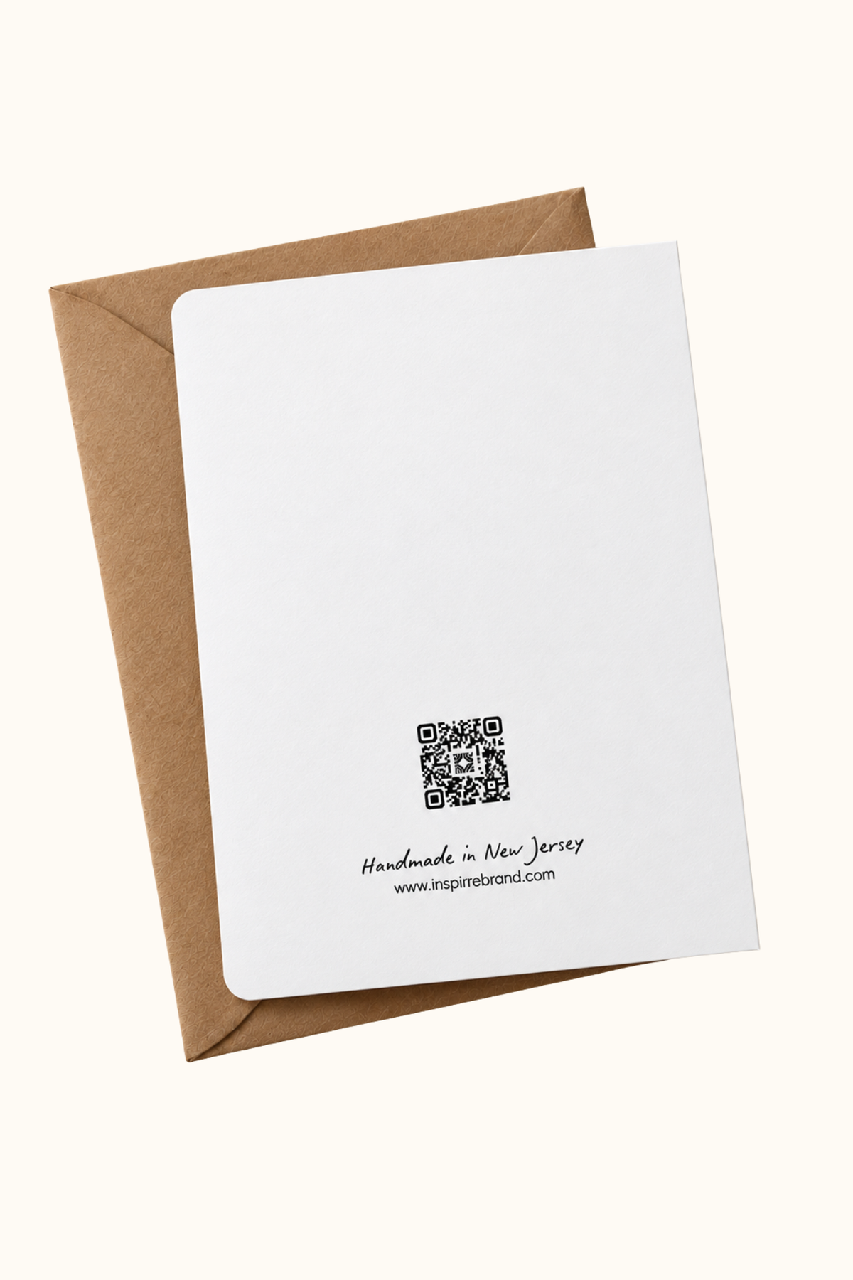 A white greeting card with a black QR code and 'Handmade in New Jersey' text, shown with a brown kraft envelope on a light cream background.